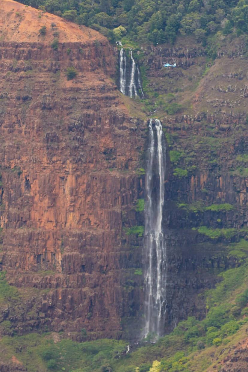 A waterfall on a cliff seen from a helicopter over Kauai, Hawaii