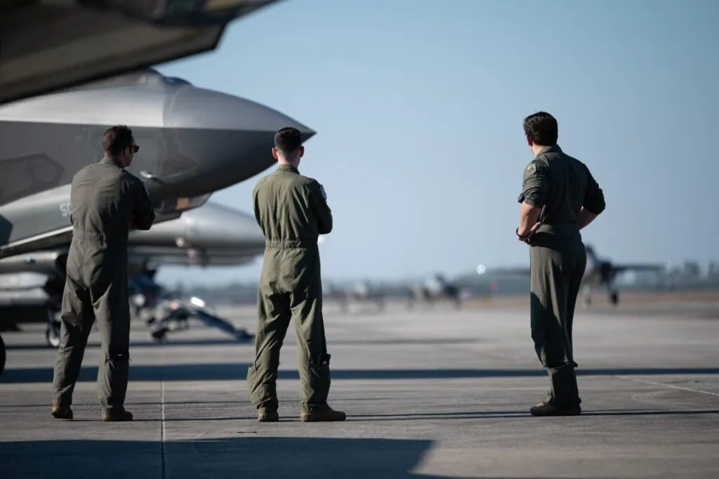 Fighter pilots standing next to military aircraft on flight line