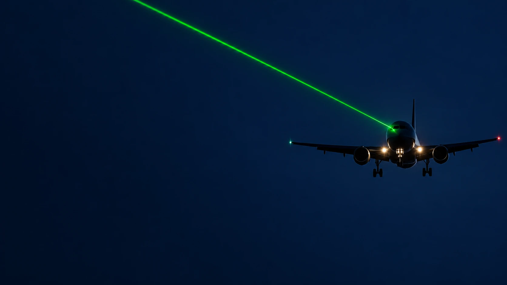 A green laser beam aimed at the cockpit of a jet on final approach