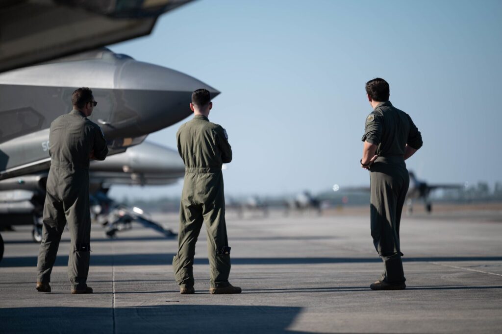 Fighter pilots standing next to military aircraft on flight line